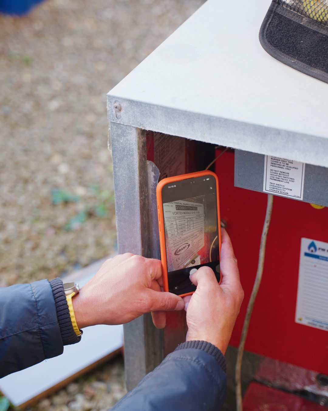 Close-up of a phone scanning the data plate inside an oil boiler casing